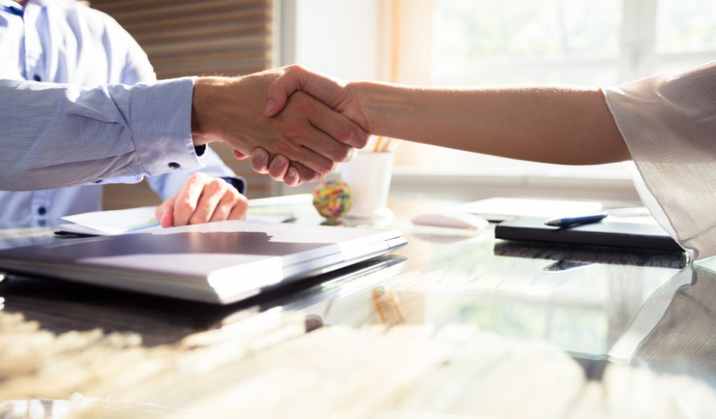 Close-up,Of,Two,Business,Partners,Shaking,Hands,Over,Desk,In